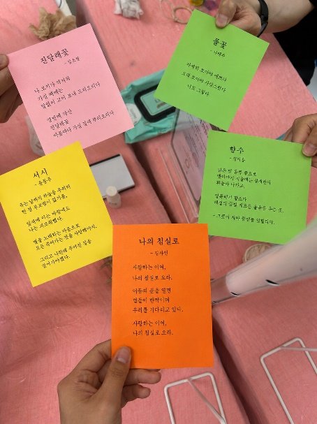 색색의 종이에 시를 옮겨 적어 손에 들고 있는 모습